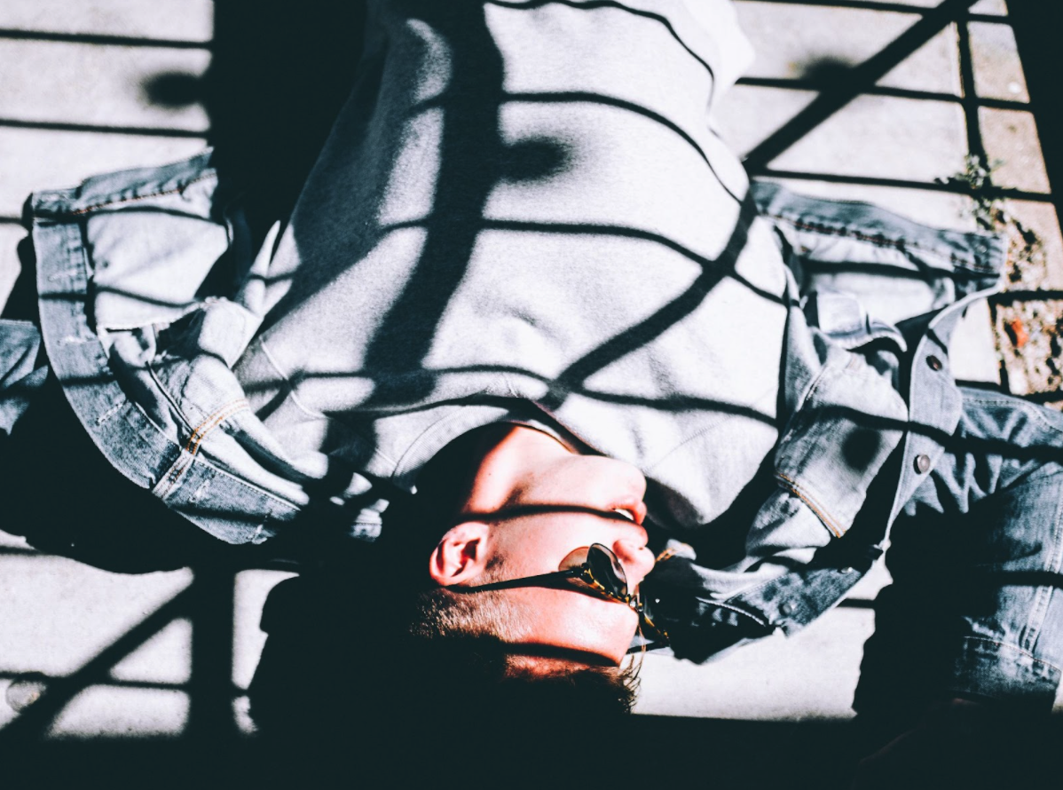 Man laying on the floow with striped shadows stretching over his body