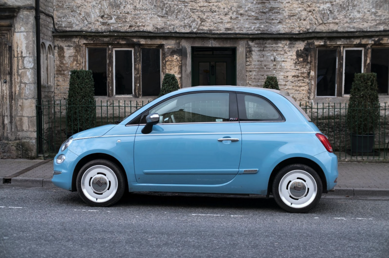 Light blue Fiat 500 car parked on street