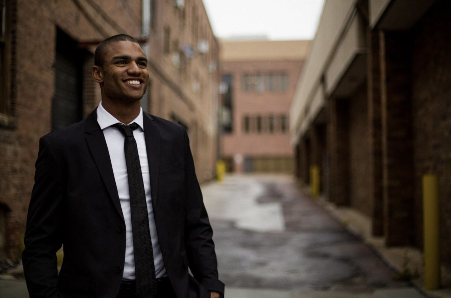 Man dressed formally standing in a narrow stree and smiling 