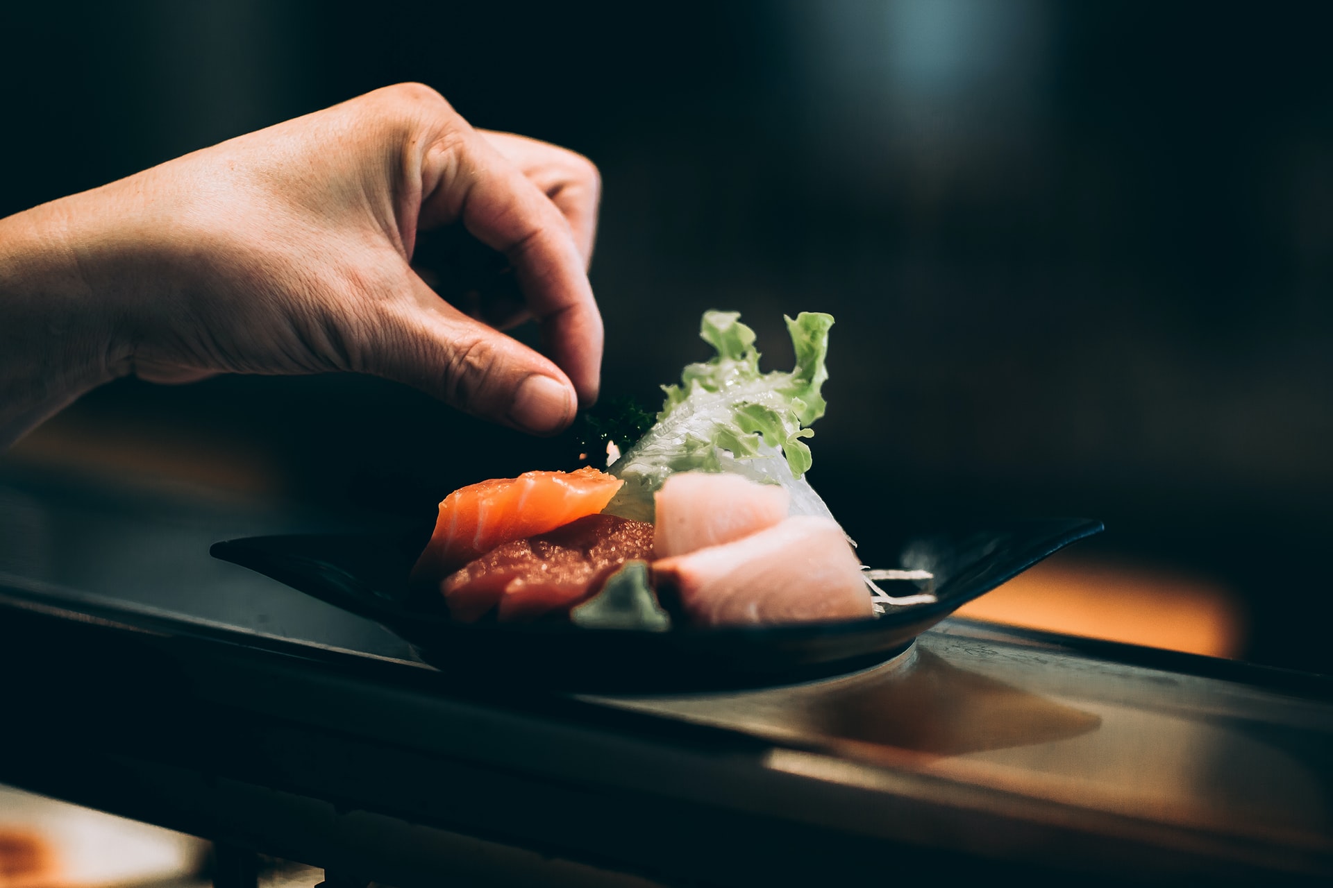 Left hand picking vegetable off a plate