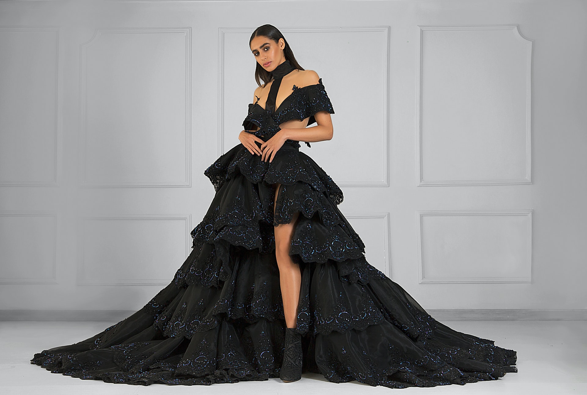 Woman with an elegant black gown standing in front of a white wall